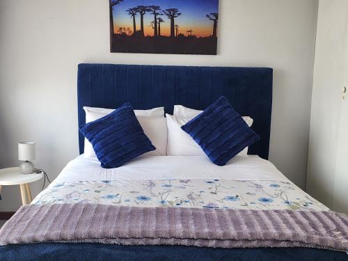 - un lit avec une tête de lit bleue et des oreillers bleus dans l'établissement Faerie Glen Heights-No Load Shedding, à Pretoria