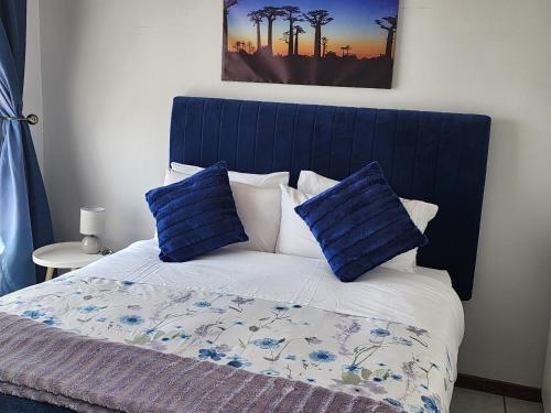 - un lit avec une tête de lit bleue et 2 oreillers bleus dans l'établissement Faerie Glen Heights-No Load Shedding, à Pretoria
