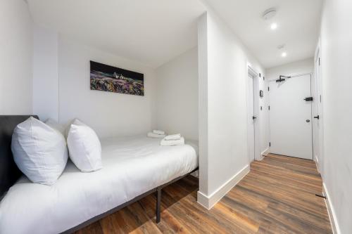 Habitación blanca con cama con almohadas blancas en 5 - West London Brand New Loft, en Londres