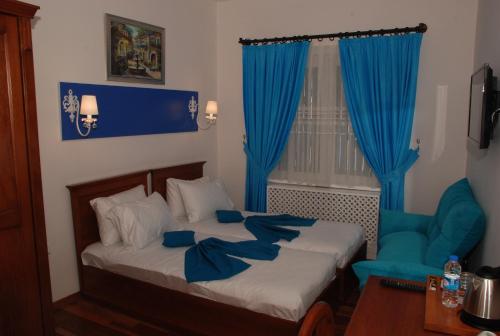 1 dormitorio con 1 cama con cortinas azules y silla en Mavi Inci Park Otel, en Erdek