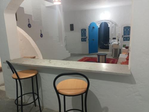dwa krzesła siedzące przy ladzie w pokoju w obiekcie Dar El Amel w mieście Mellita