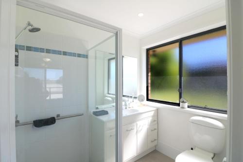 ein Bad mit einer Dusche, einem WC und einem Fenster in der Unterkunft The Views - 3 or 4 Bedroom in Tura Beach