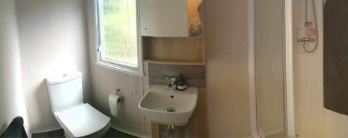 a bathroom with a white toilet and a sink at Luxury caravan in Porthmadog