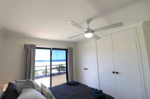 1 dormitorio con ventilador de techo, 1 cama y ventana en The Views - 3 or 4 Bedroom, en Tura Beach