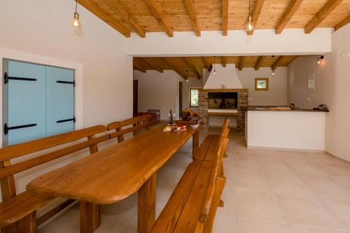 a dining room with a long wooden table and benches at Villa Copun with heated pool in Rab