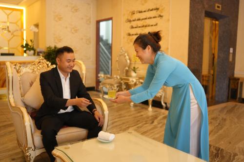a woman is handing a man a drink at Pleiku & Em Hotel by Gia Lai Tourist in Pleiku