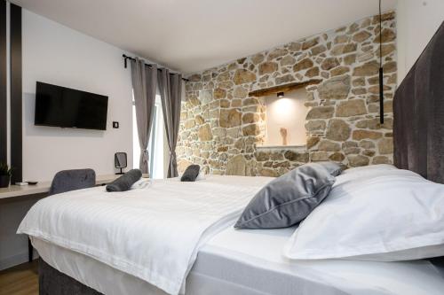 a bedroom with a large bed with a stone wall at Villa Copun with heated pool in Rab