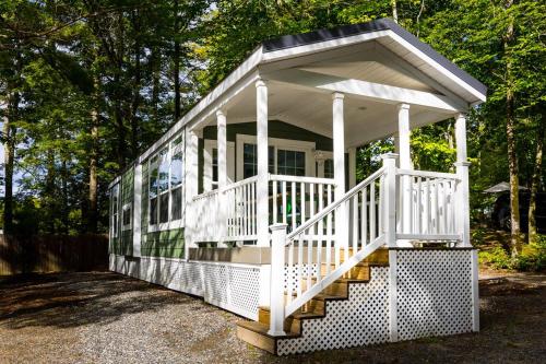 a white house with a white porch and stairs at Point Sebago Resort in Casco