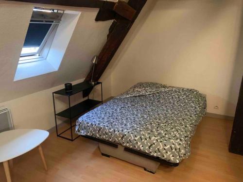 a bedroom with a bed and a table and a window at Le nid d’aigles in Dole