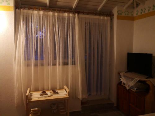 um quarto com uma janela com cortinas brancas e uma televisão em Dalaman Karia Thermal Spa Homes em Ortaca