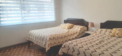 a bedroom with two beds and a window at MI ESTANCIA HOSPEDAJE in Cuenca