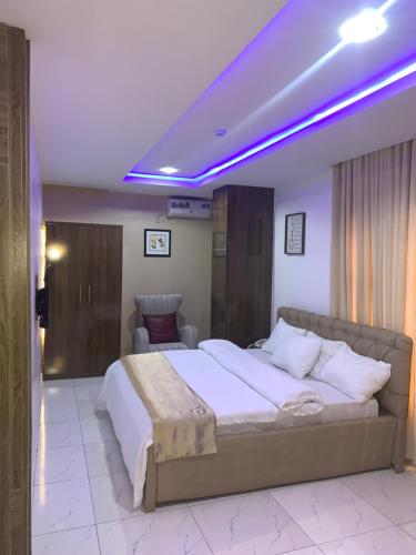 um quarto com uma cama grande e iluminação roxa em Executive Royal Suite Kado em Abuja