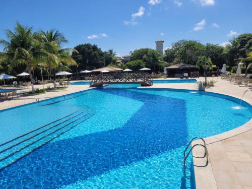 ein großer Swimmingpool mit blauem Wasser in einem Resort in der Unterkunft Genipabu Club House Guarajuba Camaçari-Ba in Camaçari