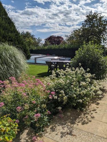un jardin avec des fleurs roses et blanches et une table dans l'établissement Le Gîte des Marronniers - location 3* avec piscine, à Ceaux-en-Loudun