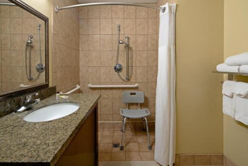 a bathroom with a sink and a shower and a chair at Staybridge Suites Palmdale, an IHG Hotel in Palmdale