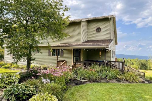 a green house with a porch and flowers at Spacious Hammondsport Home on 6 Acres with Lake View in Hammondsport
