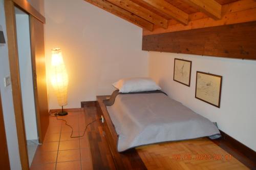 Un dormitorio pequeño con una cama y una lámpara. en Gli appartamenti del Casino dei Civili, en Trecastagni