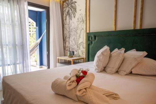 a bedroom with a bed with towels and flowers on it at Exótica Boutique Hotel in Pipa