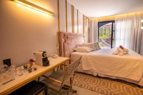 a bedroom with a bed and a desk and a window at Exótica Boutique Hotel in Pipa