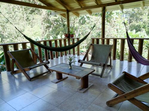 eine Veranda mit 2 Stühlen, einem Tisch und einer Hängematte in der Unterkunft La Chonta in Mindo