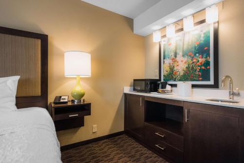 a hotel room with a bed and a sink and a lamp at Hampton Inn Meridian in Meridian
