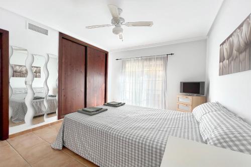 a white bedroom with a bed and a tv at Roda, Sea and Golf in Roda