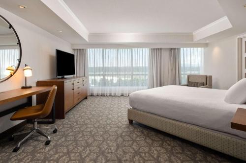 a hotel room with a bed and a desk and a mirror at Embassy Suites by Hilton Portland Airport in Portland