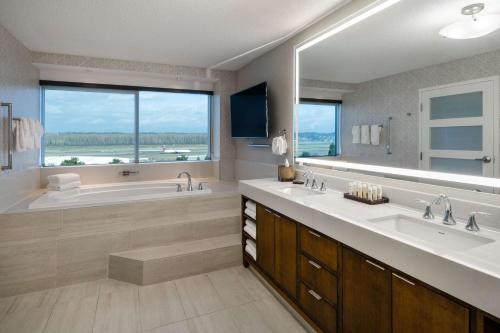 baño con 2 lavabos y bañera con ventana grande en Embassy Suites by Hilton Portland Airport en Portland