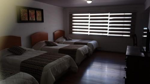 una camera con due letti e una finestra con persiane di Hotel El Gourmet a La Calera