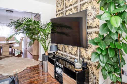a living room with a tv on a wall with plants at Anfield House by LFC Stadium in Liverpool