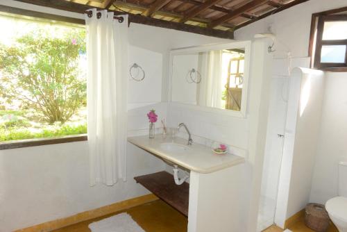 baño con lavabo, espejo y ventana en Casa Franco Hospedaria, en Trancoso