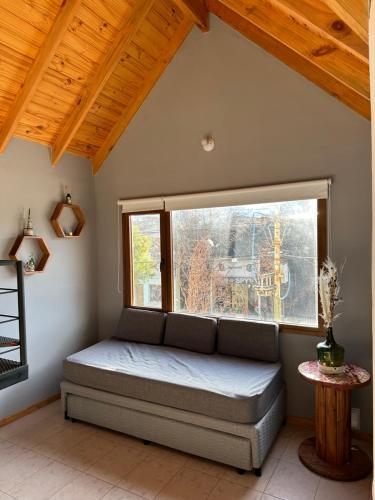 Cama en habitación con ventana grande en Los Alerces Patagonia Apart en Esquel