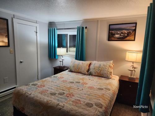 a bedroom with a bed with blue curtains and two lamps at Inn at Arch Rock in Depoe Bay