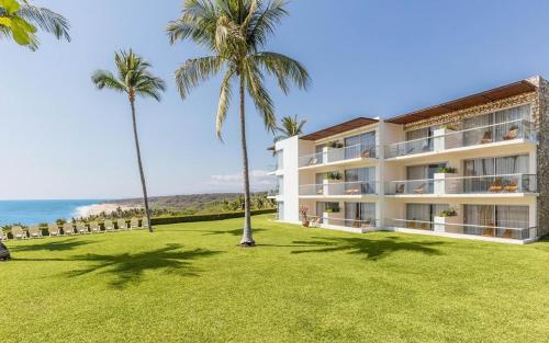 a large white building with palm trees and the ocean at Posada Real Puerto Escondido in Puerto Escondido