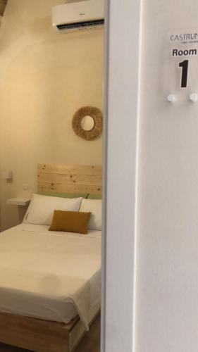 sypialnia z białym łóżkiem z drewnianym zagłówkiem w obiekcie Castrum Rooms w mieście Mesagne