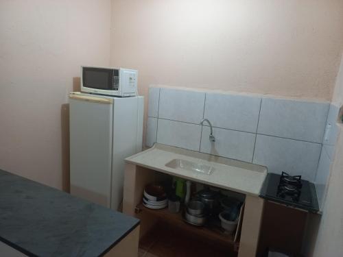 a small kitchen with a microwave on top of a refrigerator at Locação p final de semana Mourada Térrea in Caraguatatuba