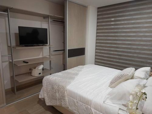 a bedroom with a white bed and a television at SuiteGreen, exclusivo apartaestudio !! in Ibagué