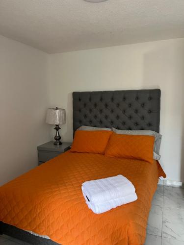 1 dormitorio con 1 cama naranja y 2 toallas en Cozy Wine Pedregal en Ciudad de México