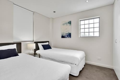 Cette chambre blanche dispose de 2 lits et d'une fenêtre. dans l'établissement Spacious Two bedroom apartment - St Leonards AL25, à Sydney
