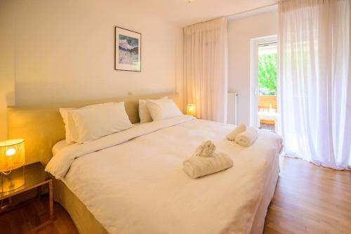 ein Schlafzimmer mit einem großen weißen Bett mit Handtüchern darauf in der Unterkunft Seaside 2 BR Boho Minimal Apartment 80m Beachfront in Athen