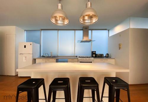una cucina con un grande tavolo bianco con quattro sgabelli di Two bedroom apartment in the heart of La Roma a Città del Messico