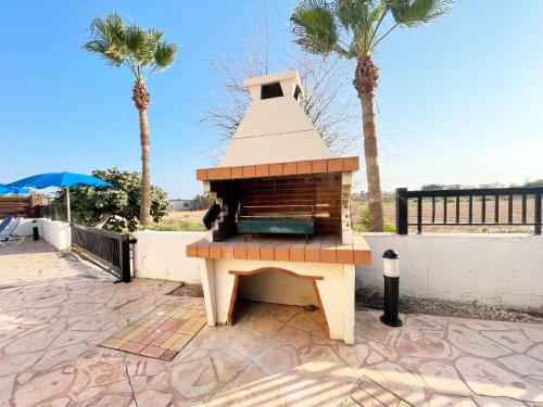 a grill sitting on a patio with palm trees at Sunset Pearl Holiday Villa in Ayia Napa