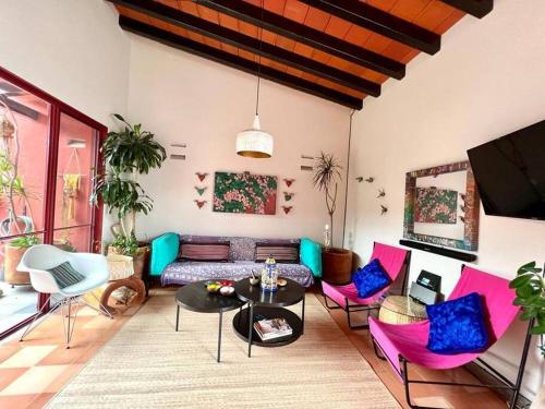 een woonkamer met roze en blauwe stoelen en een bank bij Casa Jacarandas in Chapala