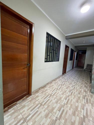 a hallway with a wooden door and a tile floor at MAHANAIMS in Tingo María