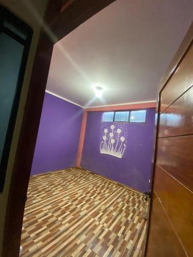 a room with a purple wall with a bed in it at MAHANAIMS in Tingo María