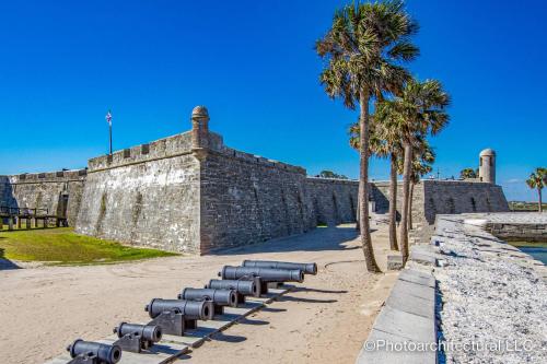 a stone wall with a row of cannons and a palm tree at 102 10th St. in Saint Augustine Beach