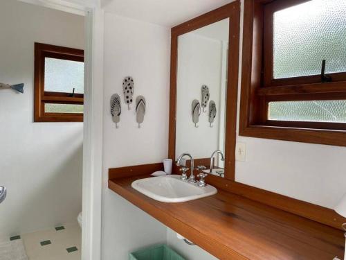 a bathroom with a sink and a mirror at Casa Deliciosa em Condo c/ Piscina Frente ao Mar in São Sebastião