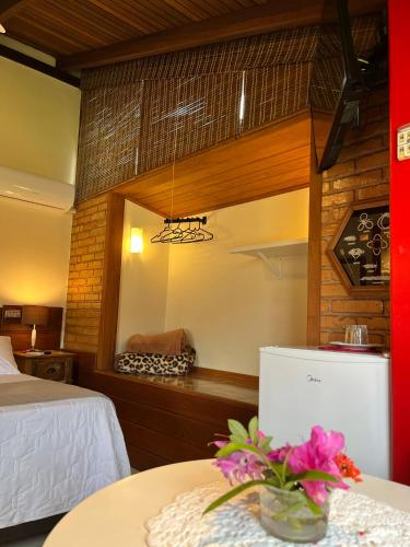 a room with a bed and a table with flowers on it at Pousada Mar de Dentro in Florianópolis