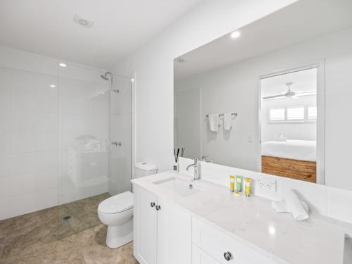 a white bathroom with a toilet and a sink at Beach City 3 Bedroom Modern Townhouse in Maroochydore