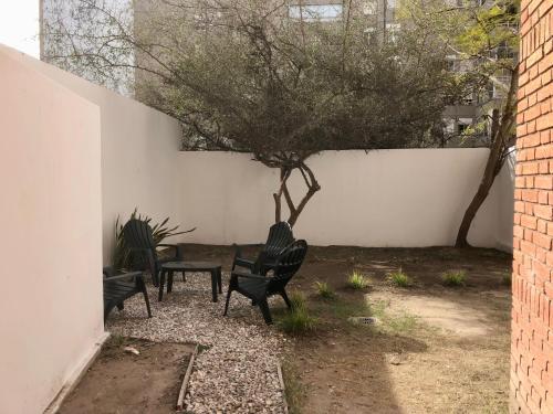 a patio with two chairs and a tree next to a wall at NvaCba Premium: a mts Pque de las Tejas, 1 dorm PB con patio, confort y diseño - ALOHA #4 in Cordoba